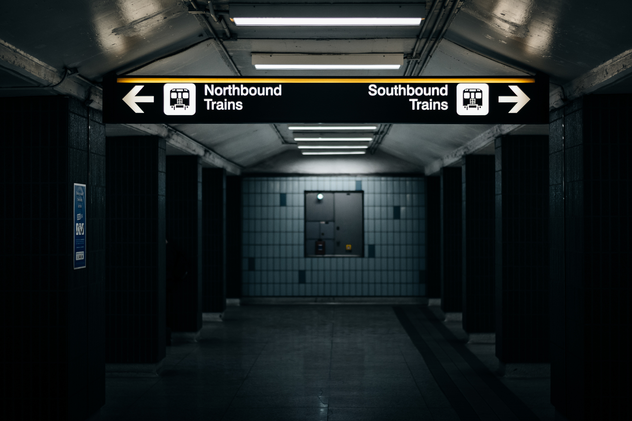 A dimly lit subway station with signs pointing to Northbound and Southbound trains