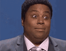 Person making a surprised facial expression in a suit and tie