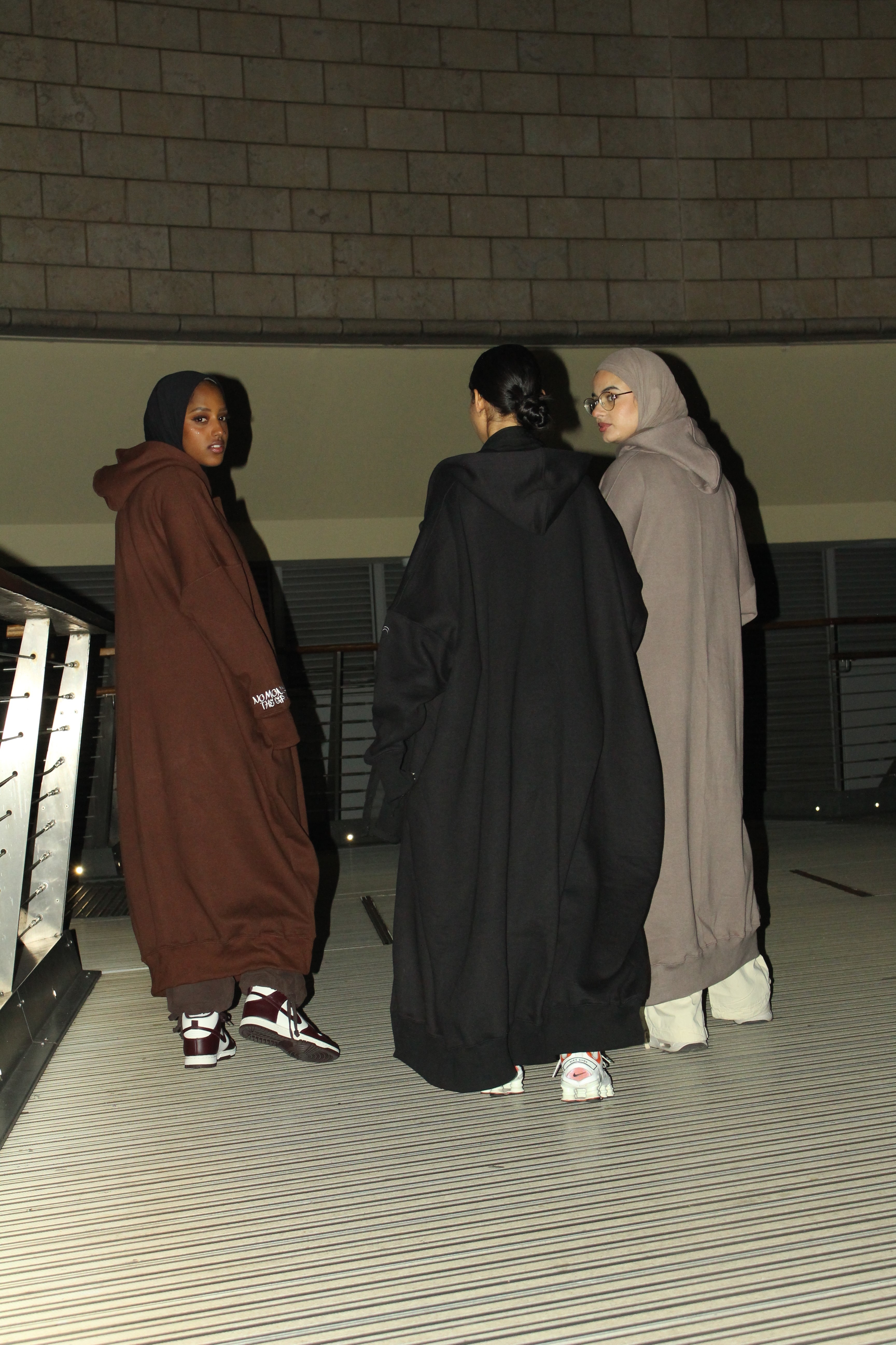 Three individuals wearing oversized hooded robes, standing in conversation