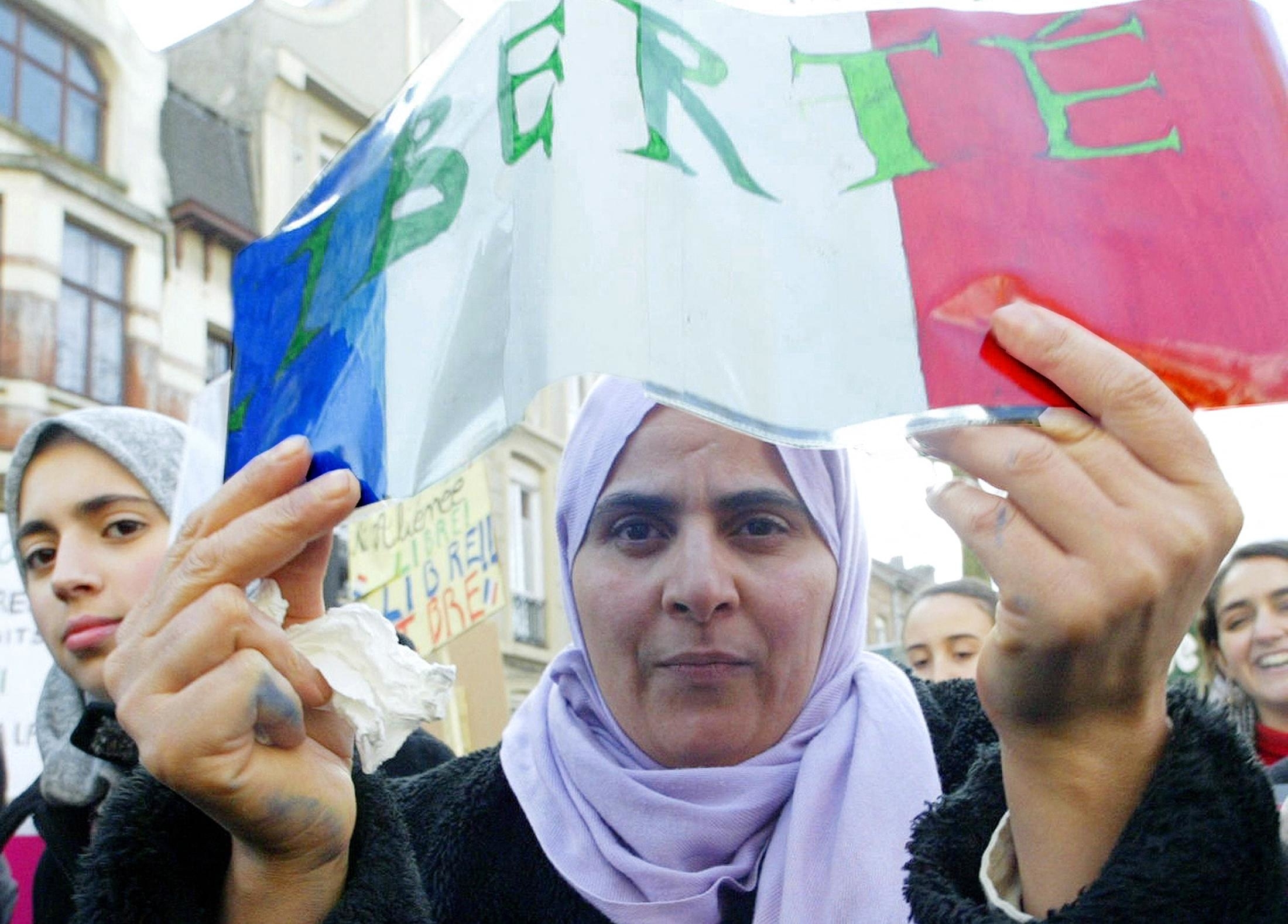 Woman holding a sign with &#x27;LIBERTE&#x27; at a demonstration, surrounded by others