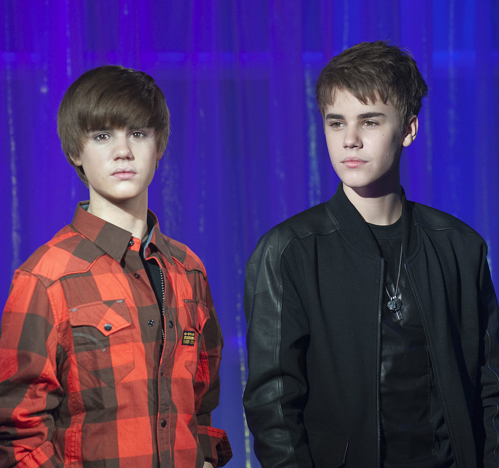 Wax figure of Justin Bieber next to the real Justin Bieber, both wearing casual tops