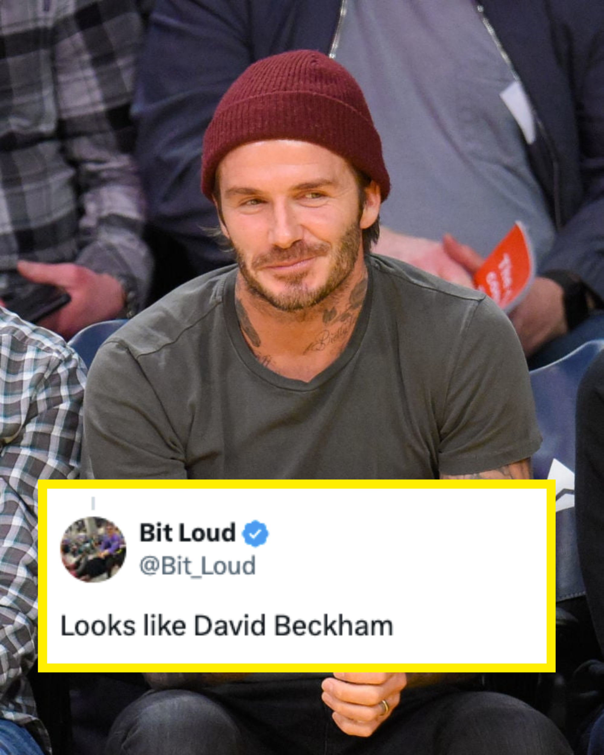 David Beckham smiling, seated, wearing a beanie and a casual shirt at a sports event