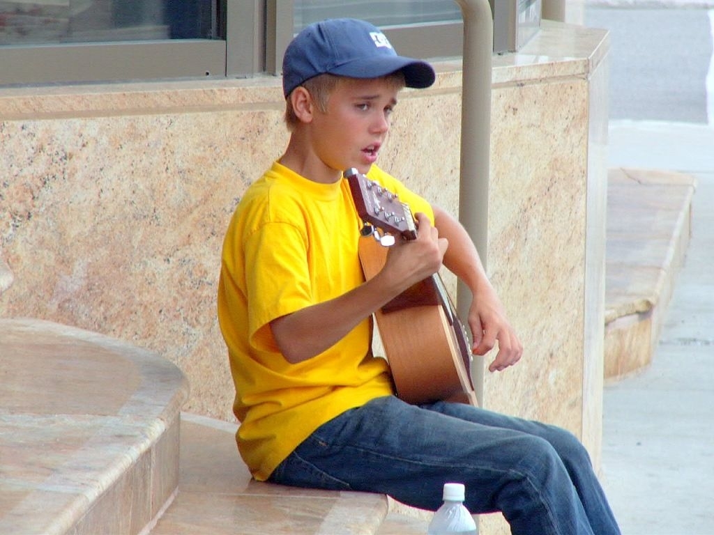 Just as a boy Boy sitting outside playing an acoustic guitar