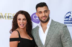 Britney Spears and Sam Asghari posing together; Britney in a black dress, Sam in a suit without a tie