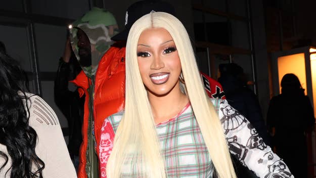 Cardi B smiling in plaid dress, long ombre hair, at a music event