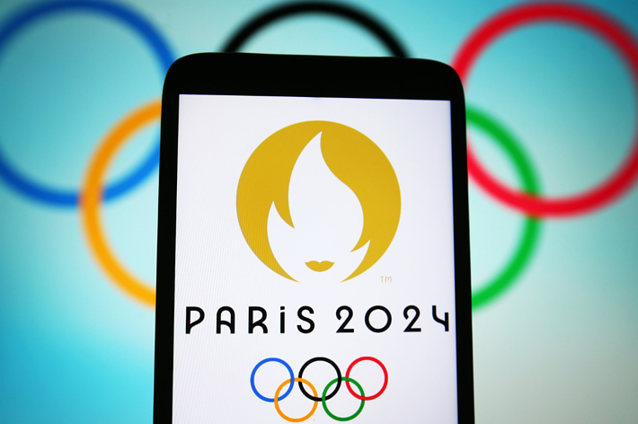 Smartphone displaying Paris 2024 Olympic logo with Olympic rings in the background