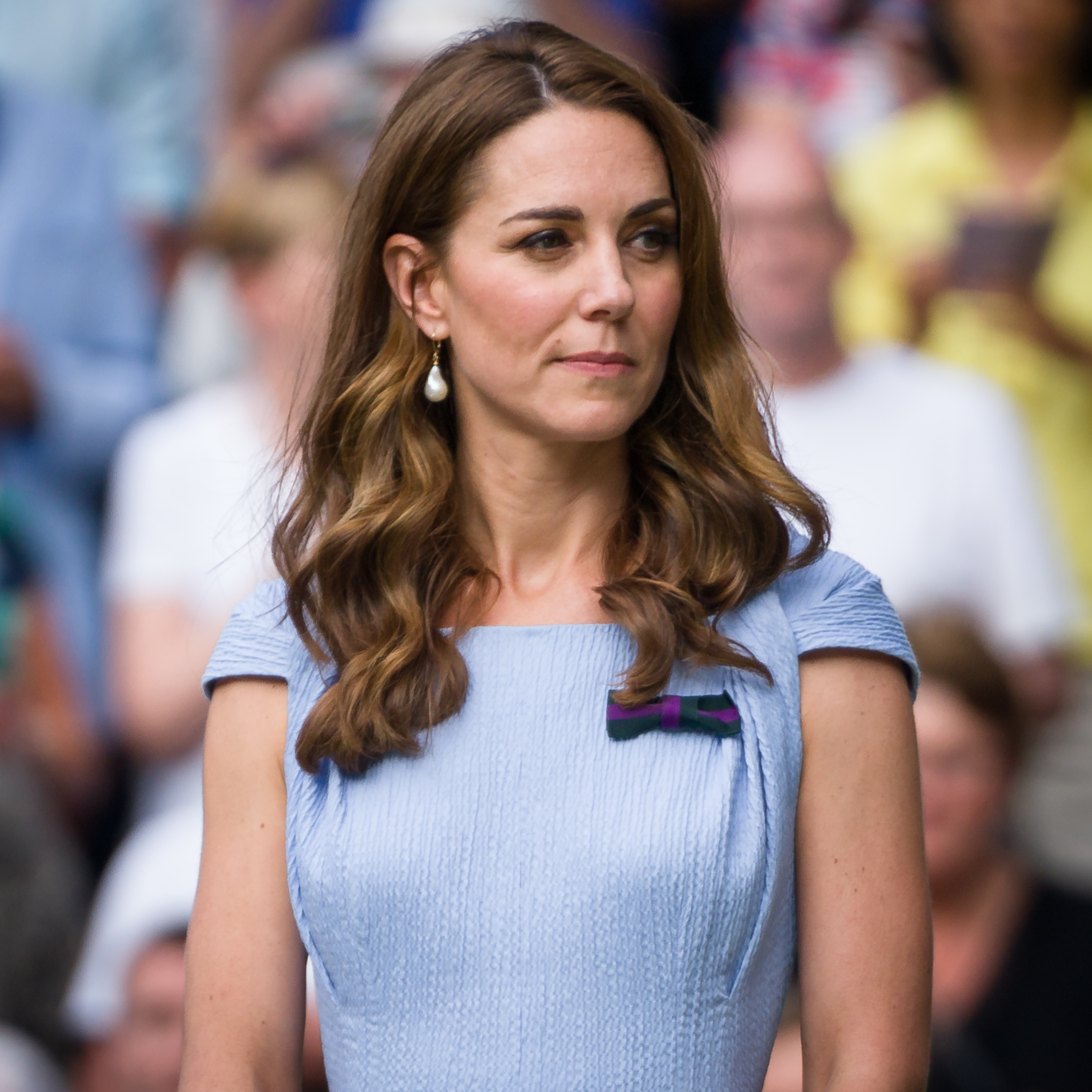 Kate Middleton in a blue dress with short sleeves and a ribbon detail, looking to the side