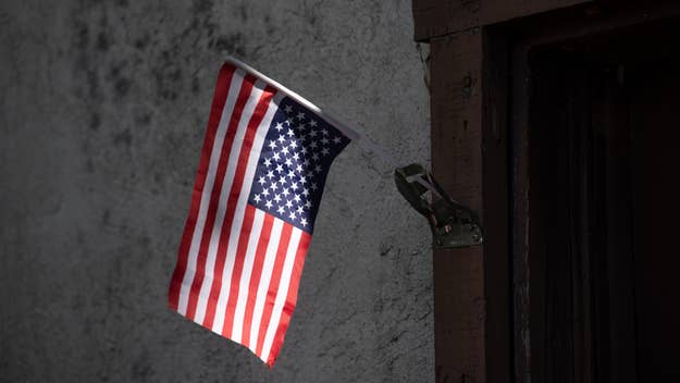 An upside-down American flag hangs from a metallic bracket on a textured wall