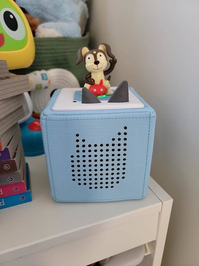 Figurine of a dog with headphones sitting on a blue fabric speaker