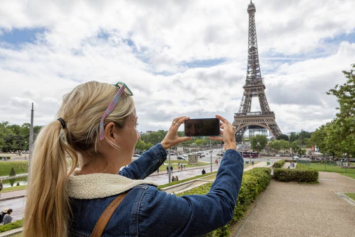 Woman taking photo of Eiffel Tower with her phone