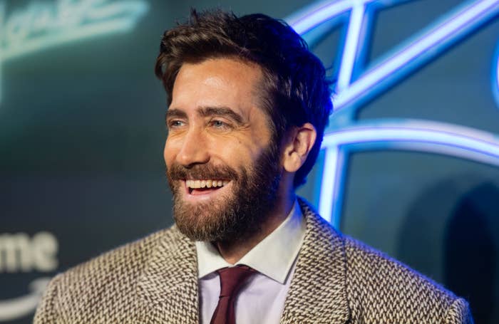 A closeup of a smiling Jake Gyllenhaal in a tweed suit at an event