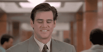 Man in a suit smiling with classic 90s hairstyle, indoors, from a popular film scene