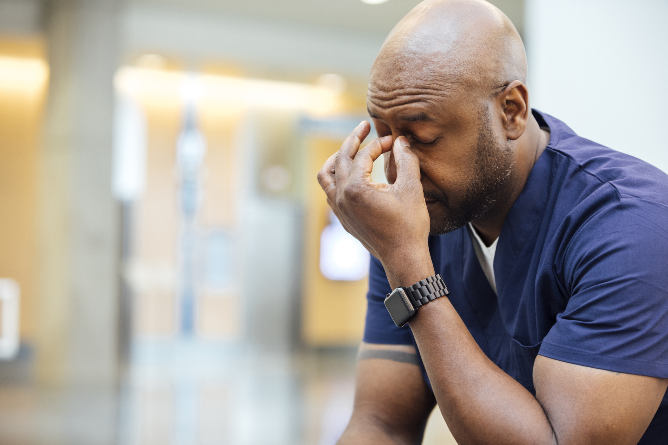A nurse looking exhausted and rubbing his eyes