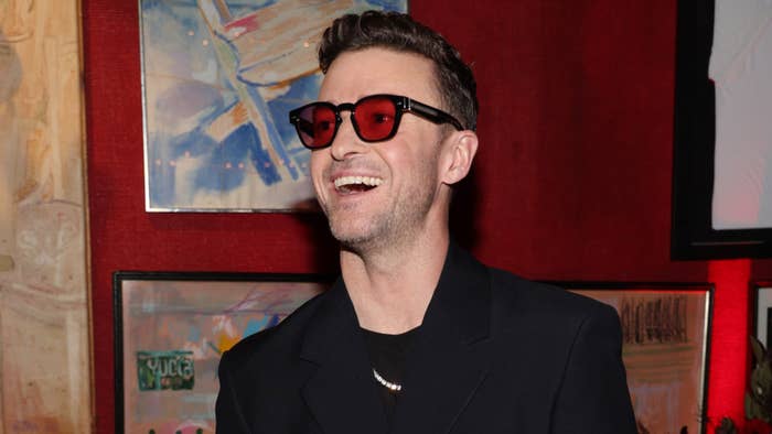 Man in red glasses and black attire laughing at an event