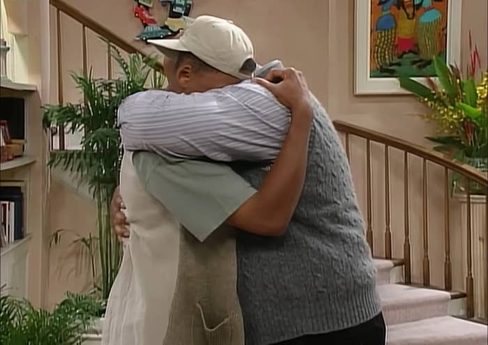 Two characters from &quot;The Fresh Prince of Bel-Air&quot; share a hug; one wears a cap and sleeveless sweater, the other a shirt