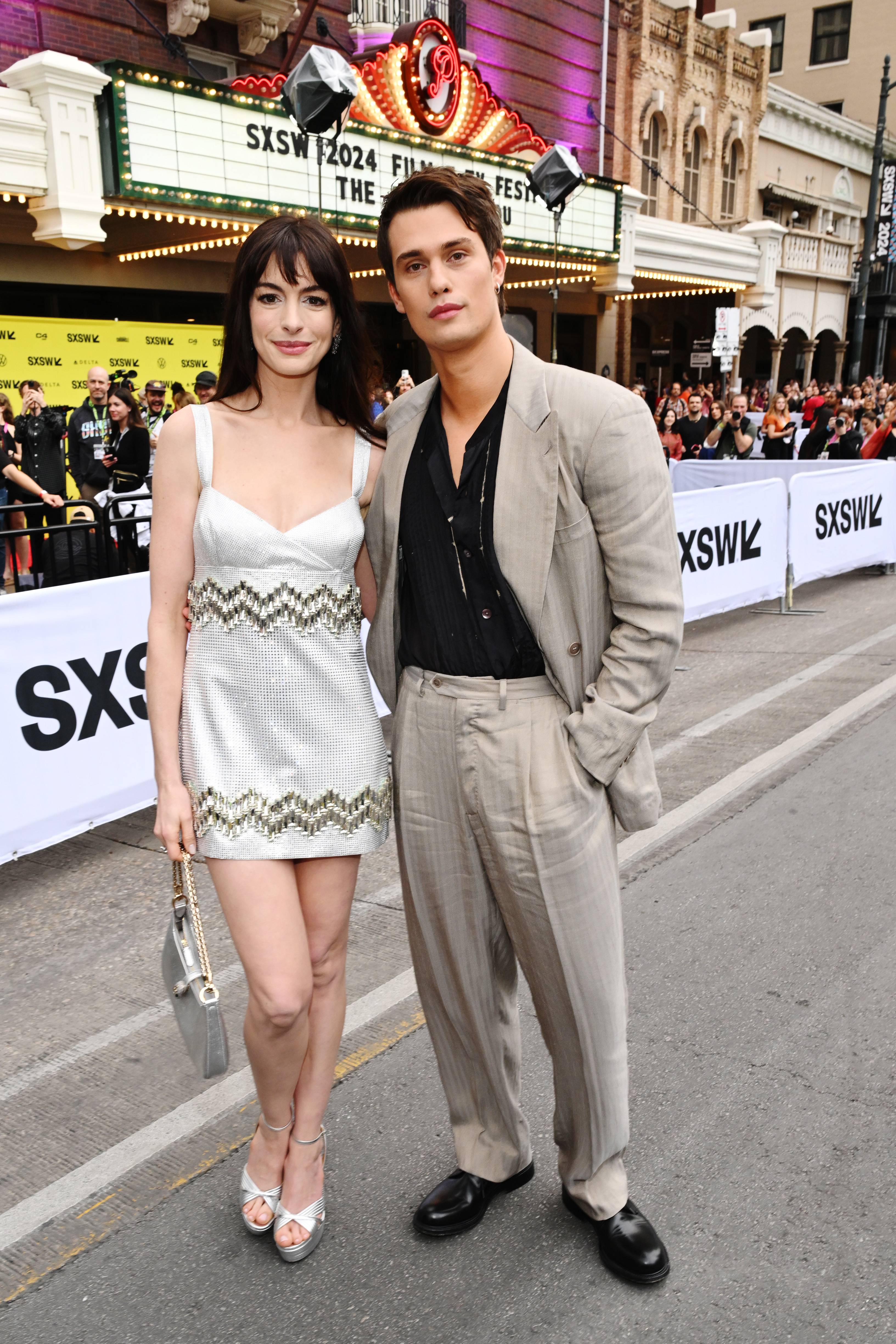 Closeup of Anne Hathaway and Nicholas Galitzine standing in the street at a SXSW event