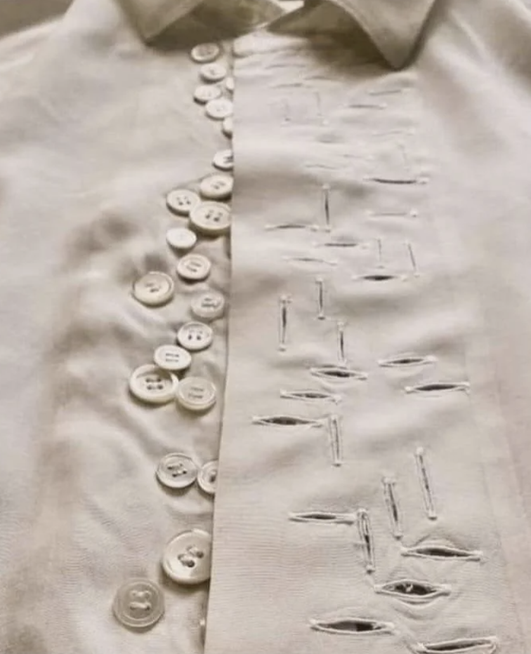 A shirt with buttons and a vertical row of stitched buttonholes, some of which are misaligned