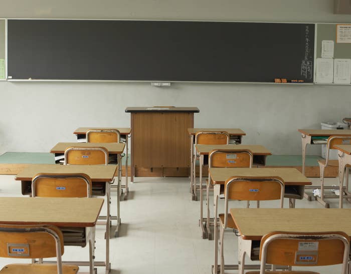 Lecture hall with rows of desks and central podium facing a large, empty blackboard