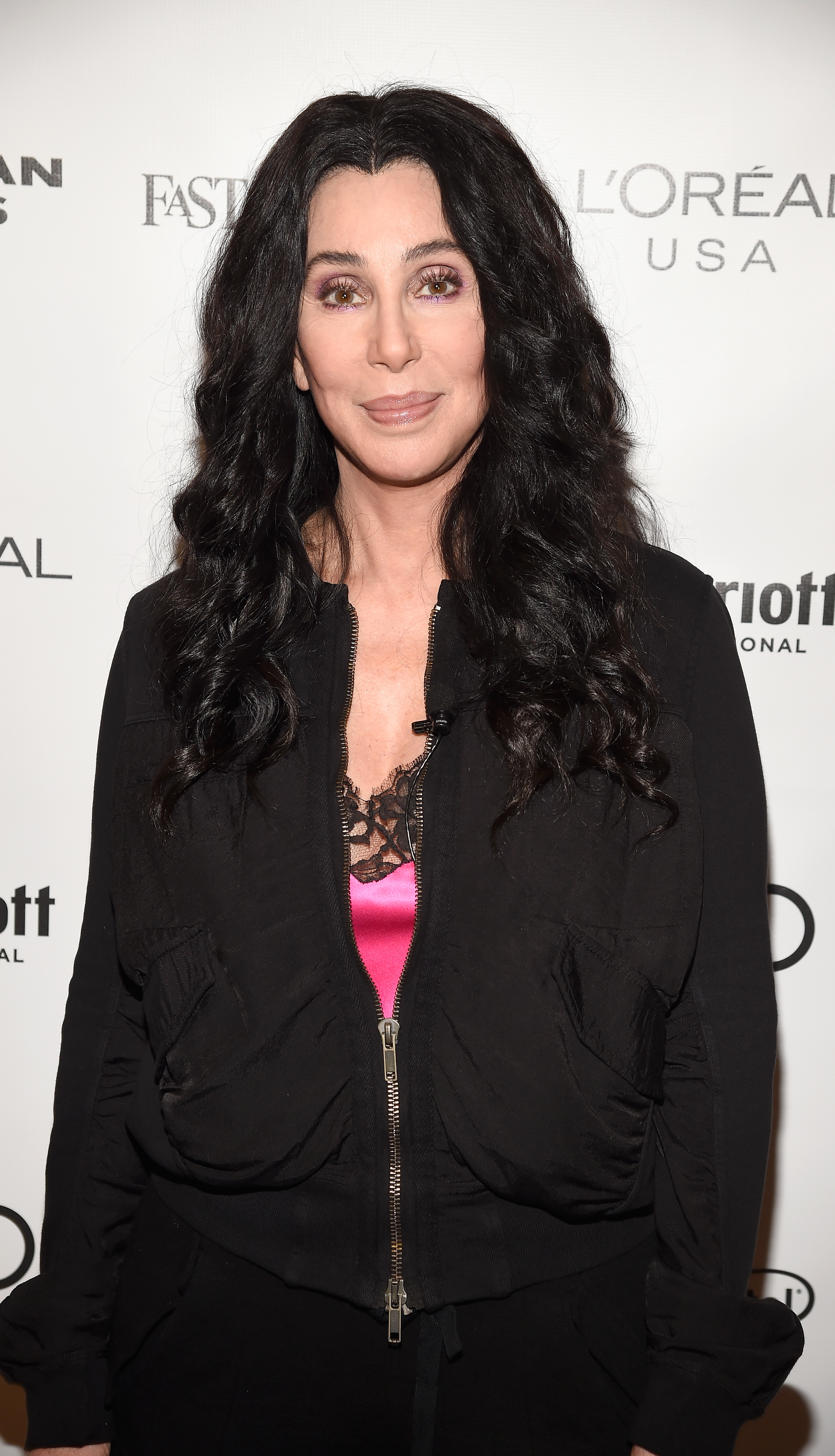 Cher in a black jacket and lace top attends an event
