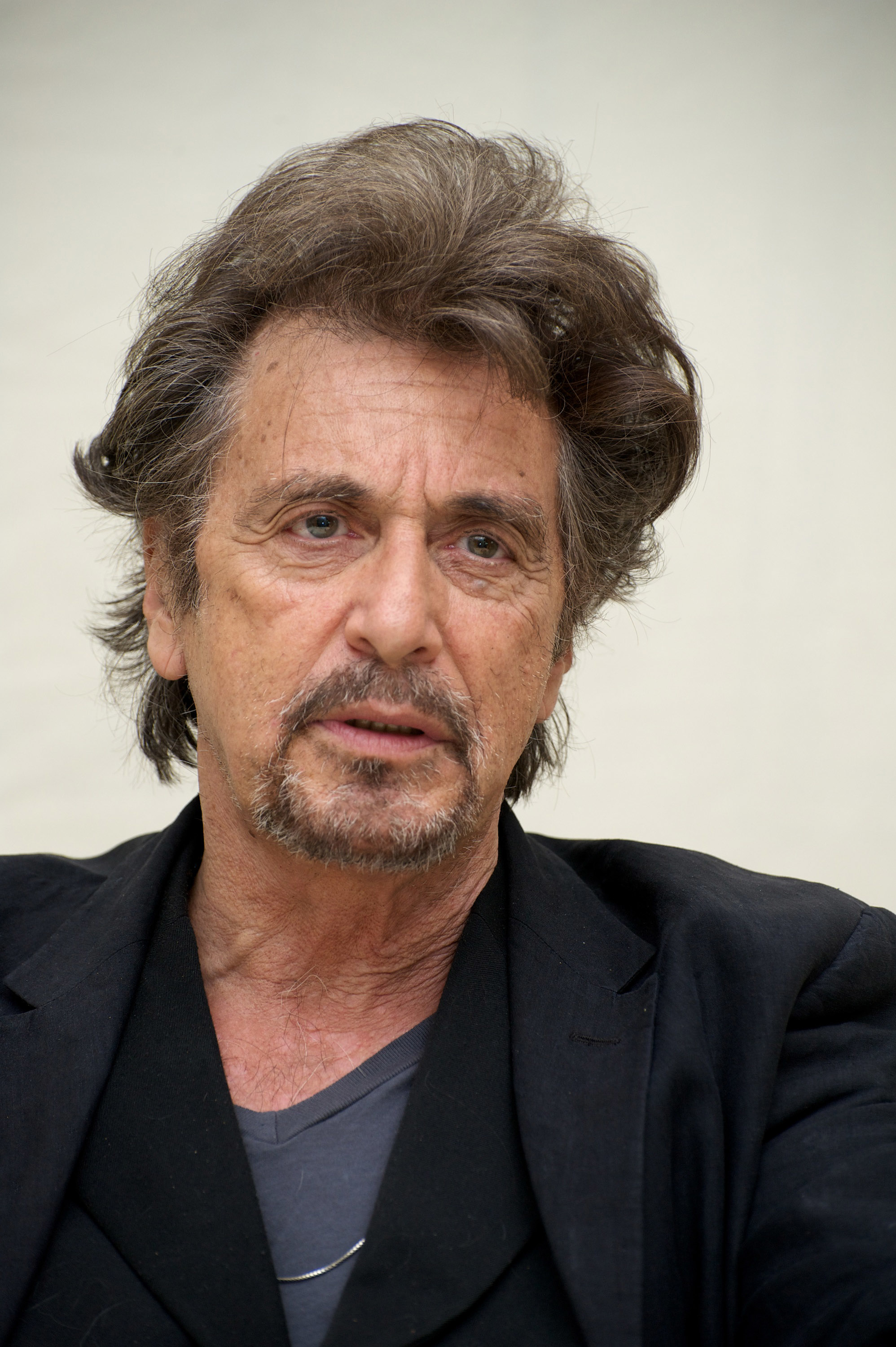 Al Pacino wearing a black suit, looking pensive