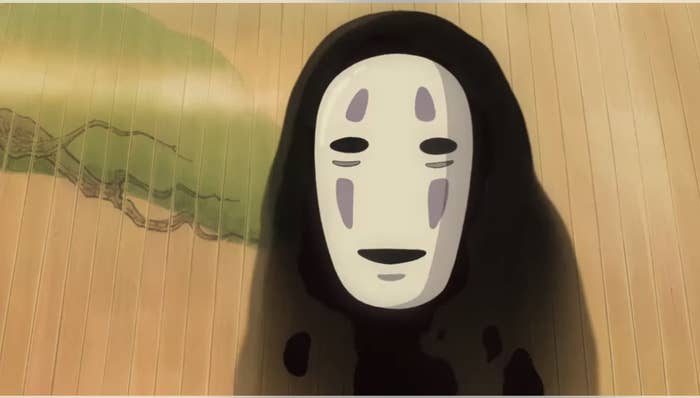 Animated character No-Face from the film &#x27;Spirited Away&#x27; standing on a wooden floor