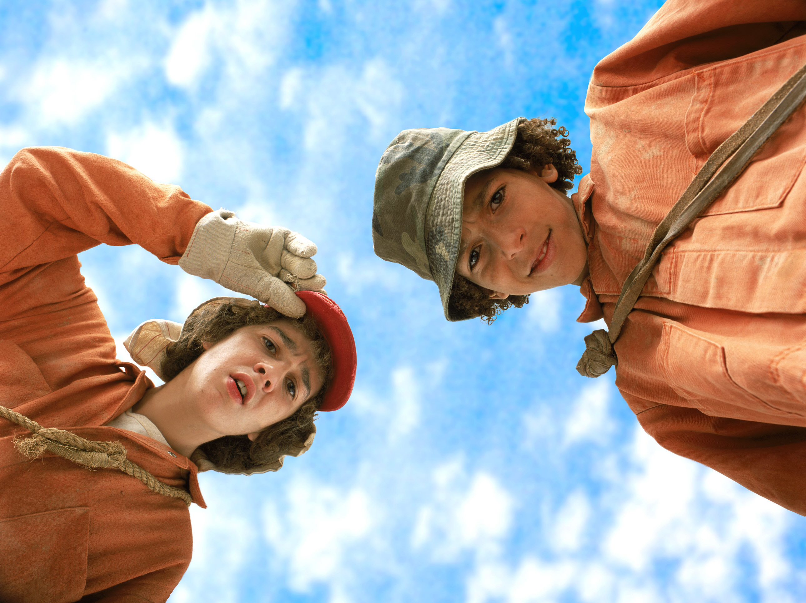 Stanley and Hector in prison jumpsuits looking down from above