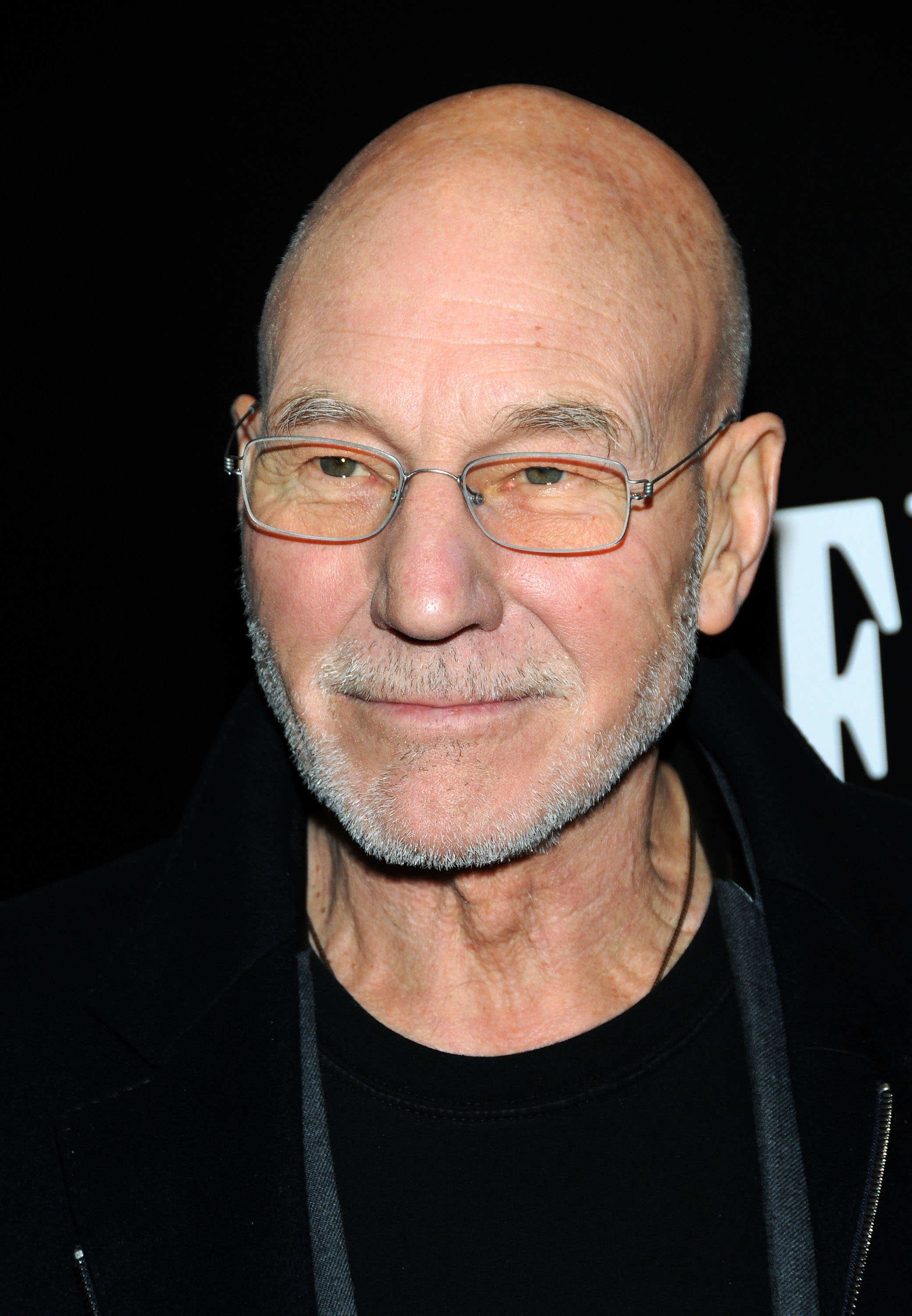 Patrick Stewart wearing glasses and a black jacket at an event