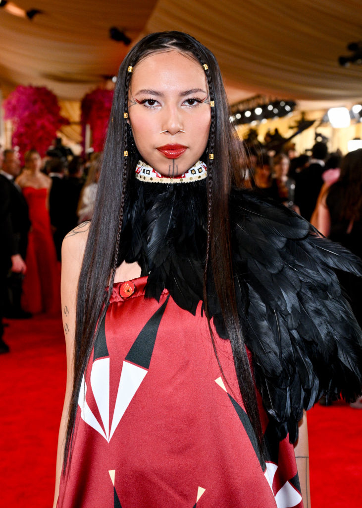 Person with beaded choker and feathered outfit at event