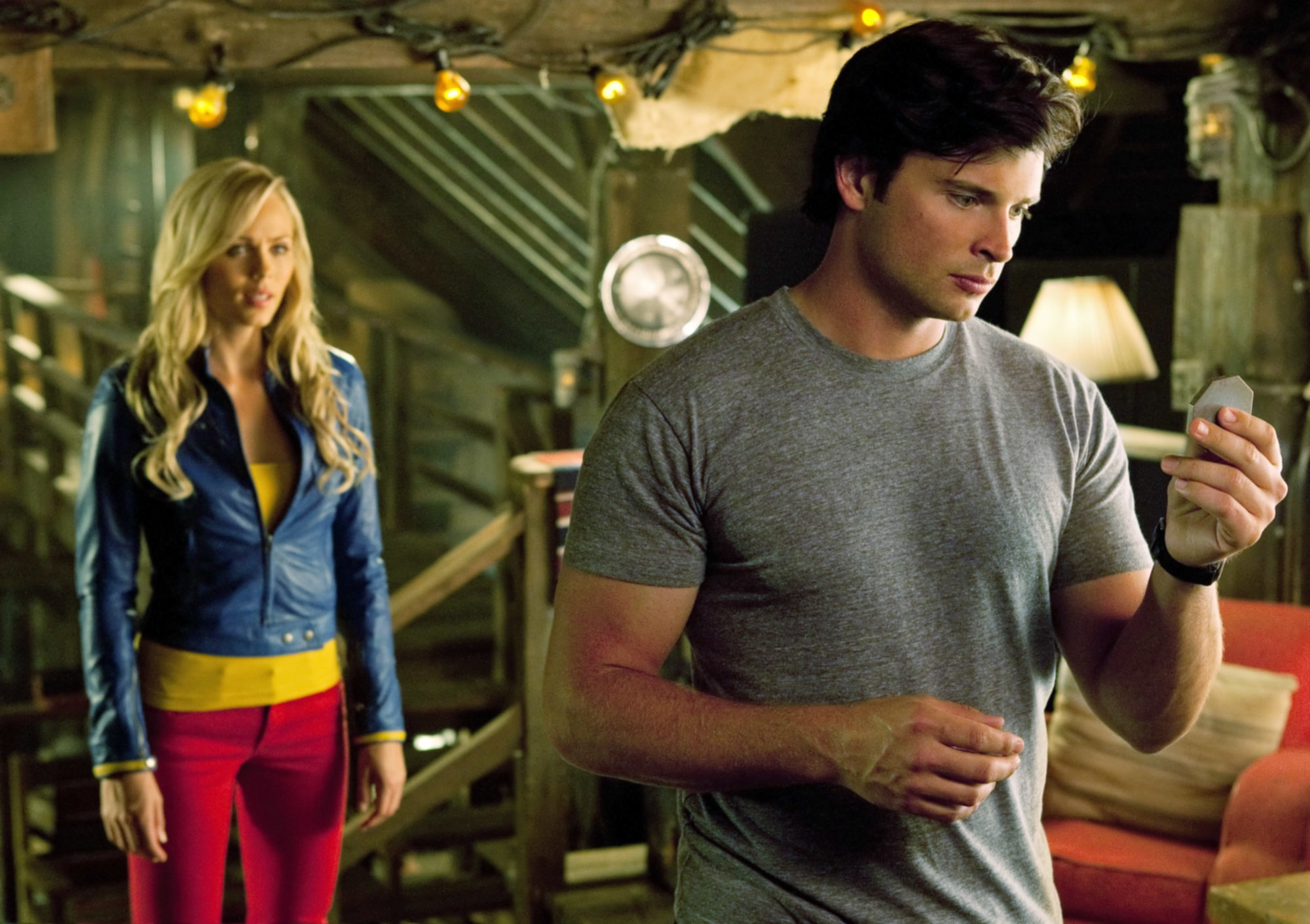 Clark Kent in a grey t-shirt and Lois Lane in a blue and yellow jacket standing in the Kent farm on Smallville