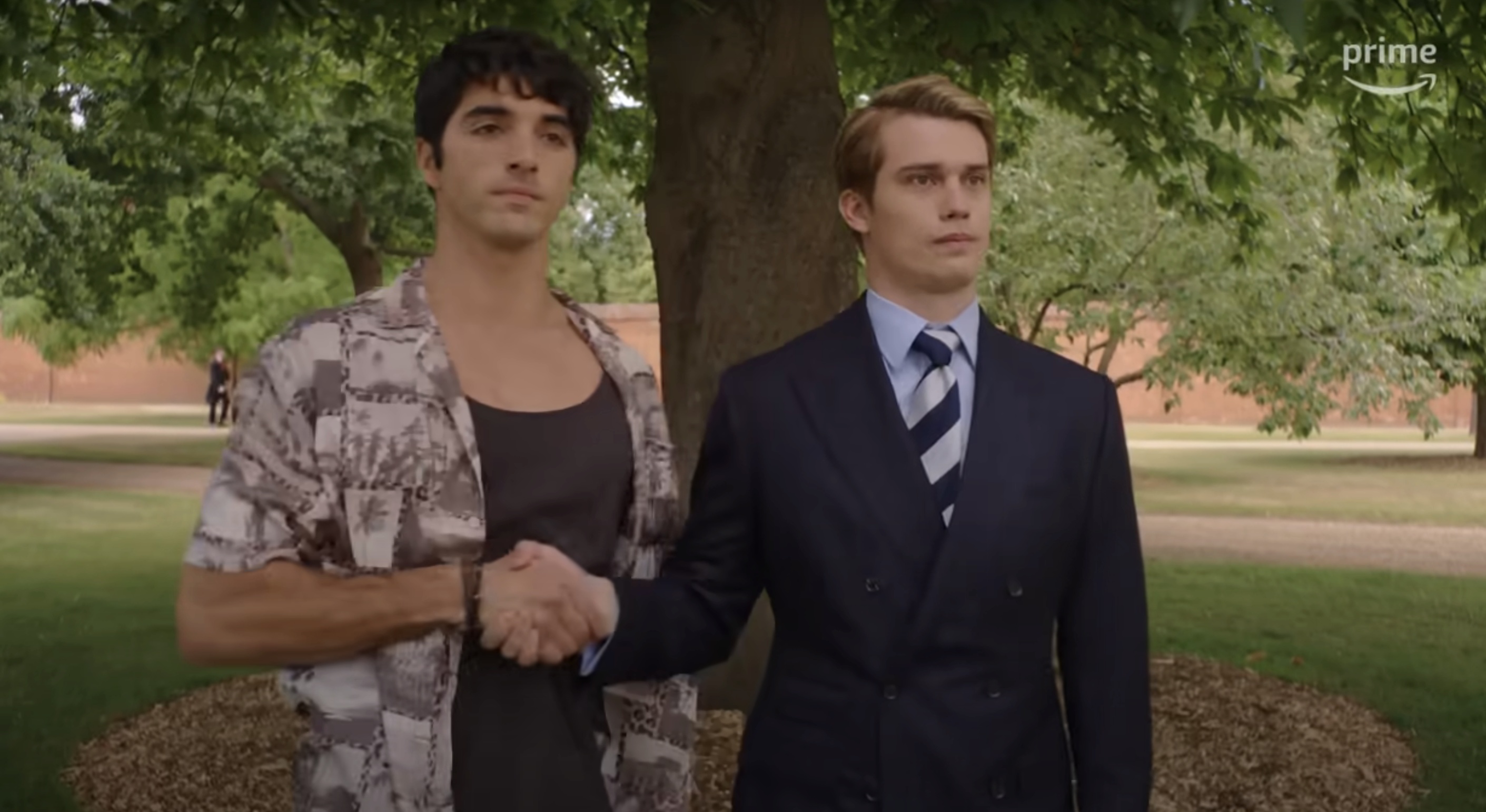 Alex casual in a patterned shirt, Henry in a suit and tie, shaking hands