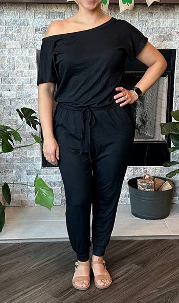 reviewer in a one-shoulder jumpsuit with tie waist and sandals