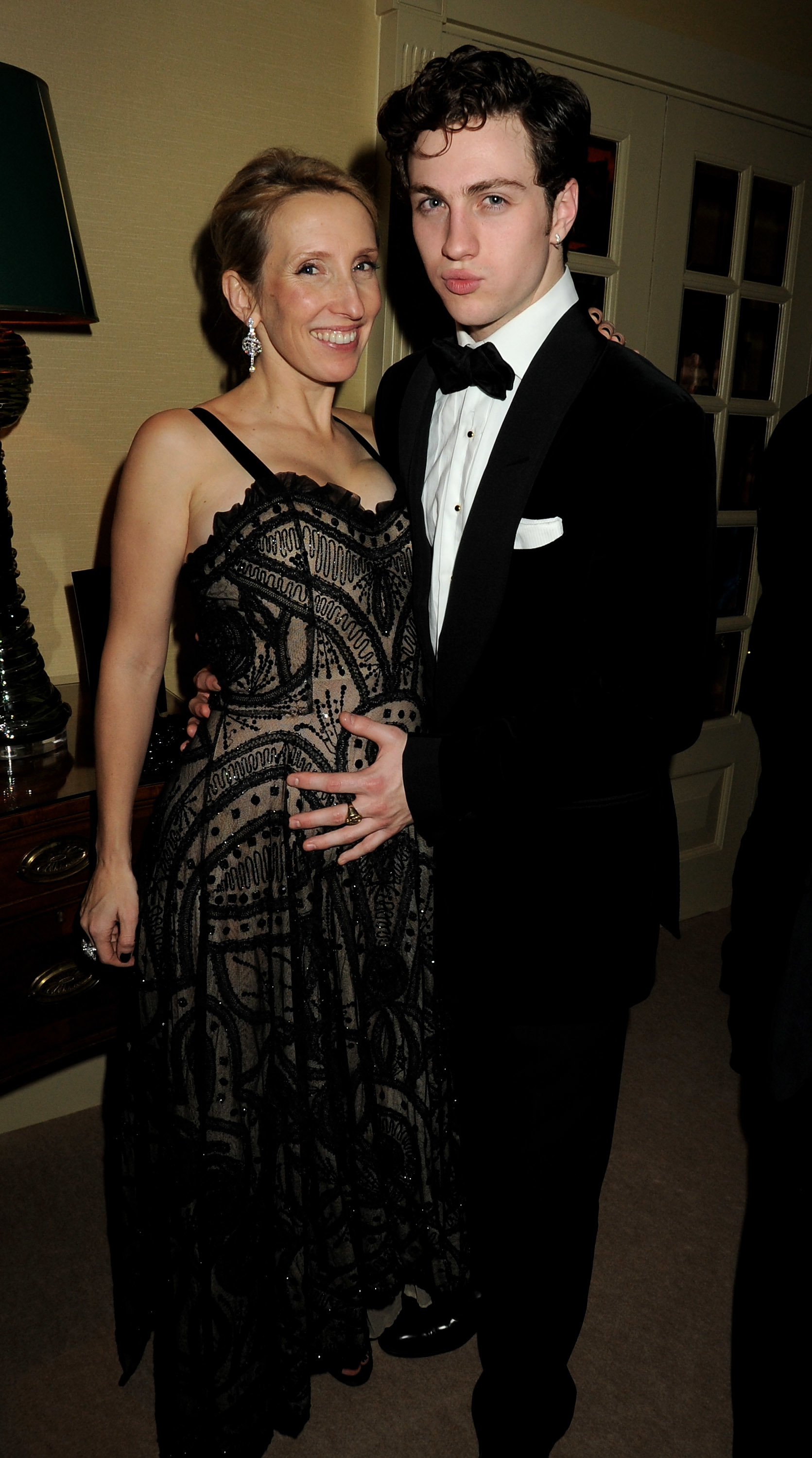 A pregnant Sam and Aaron Taylor-Johnson at a formal event smiling for a photo