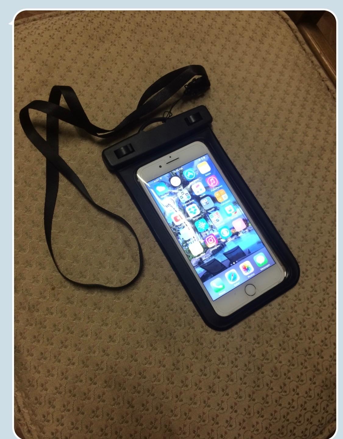 Smartphone in a waterproof case with a neck strap, on a patterned fabric surface