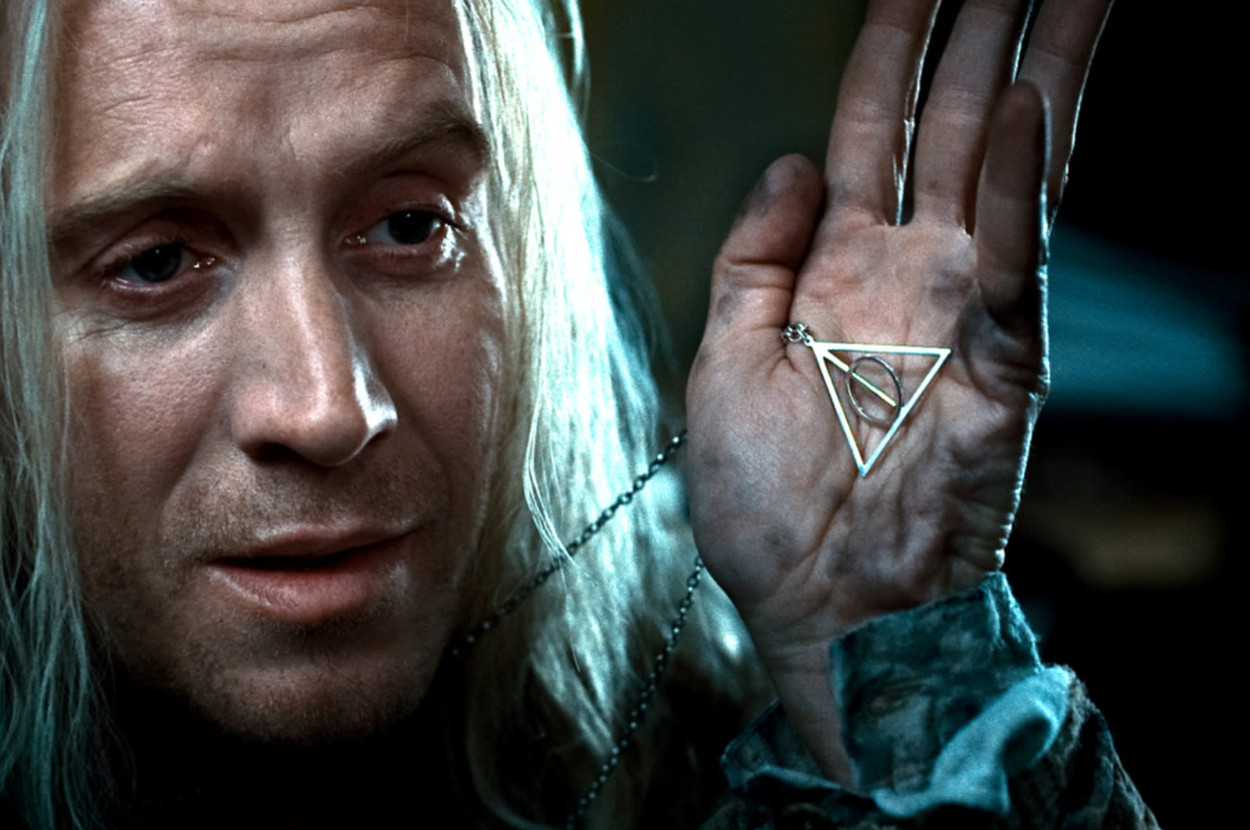 Mr. Lovegood holding up a Deathly Hallows necklace.