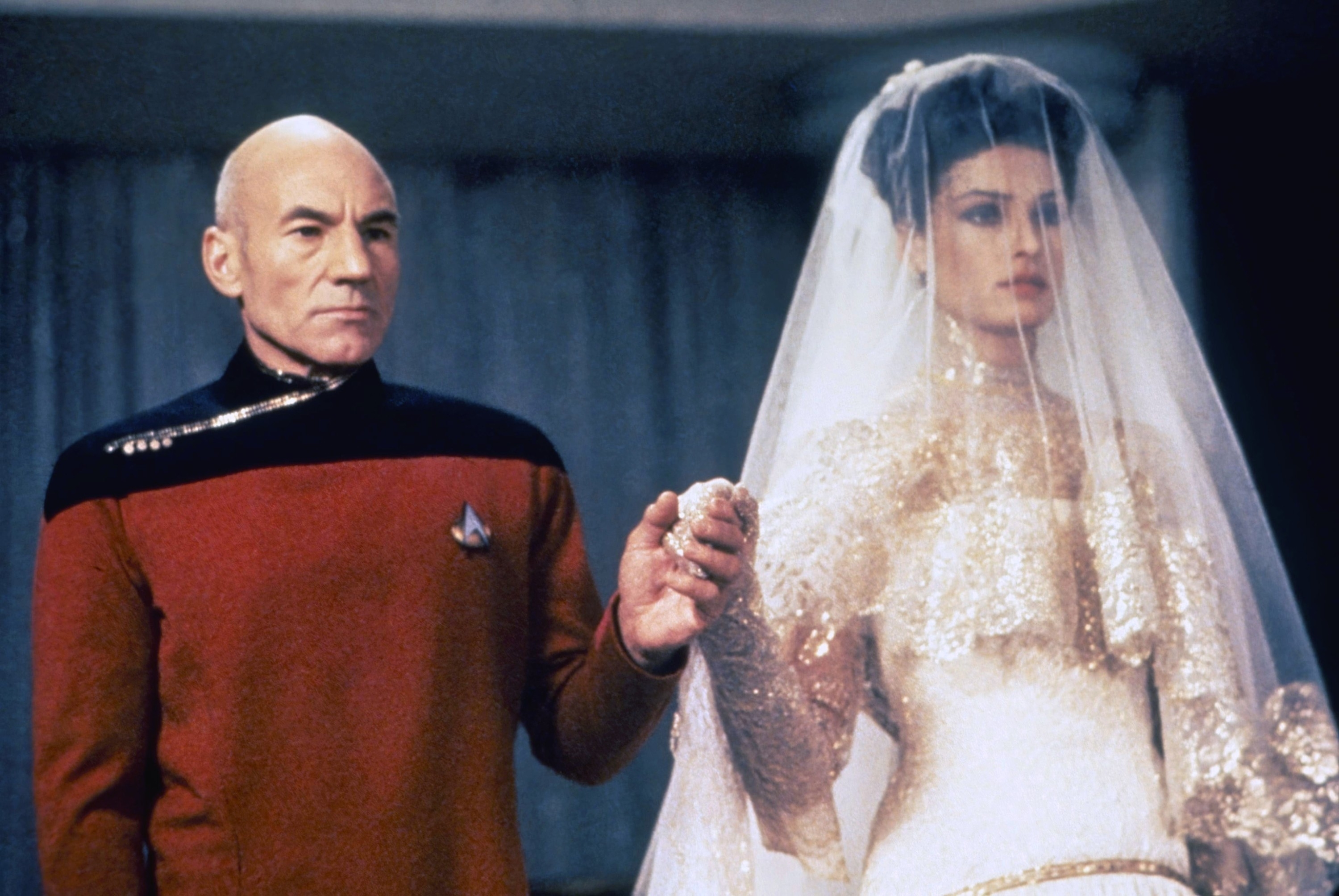 Captain Picard in uniform beside a character in a bridal gown on the Star Trek set