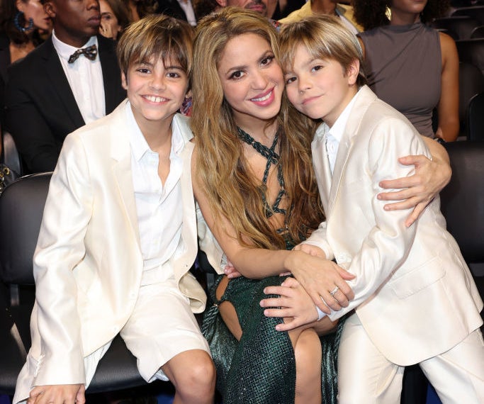 Shakira with her sons, Milan and Sasha, smiling for a photo at an event