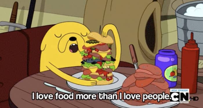 Animated character Jake from Adventure Time eating a large sandwich with text &quot;I love food more than I love people.&quot;