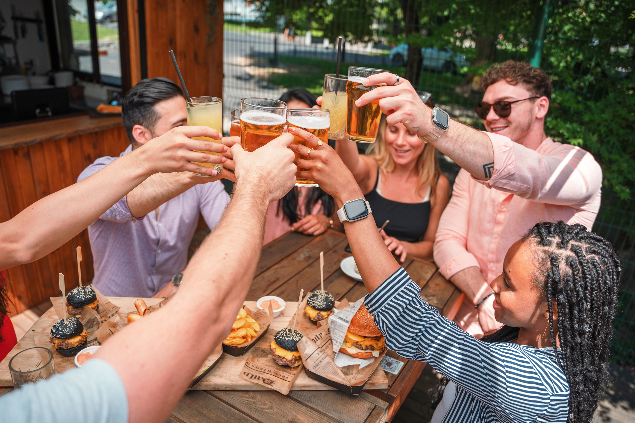 Group of friends toasting drinks at a casual outdoor dining setting