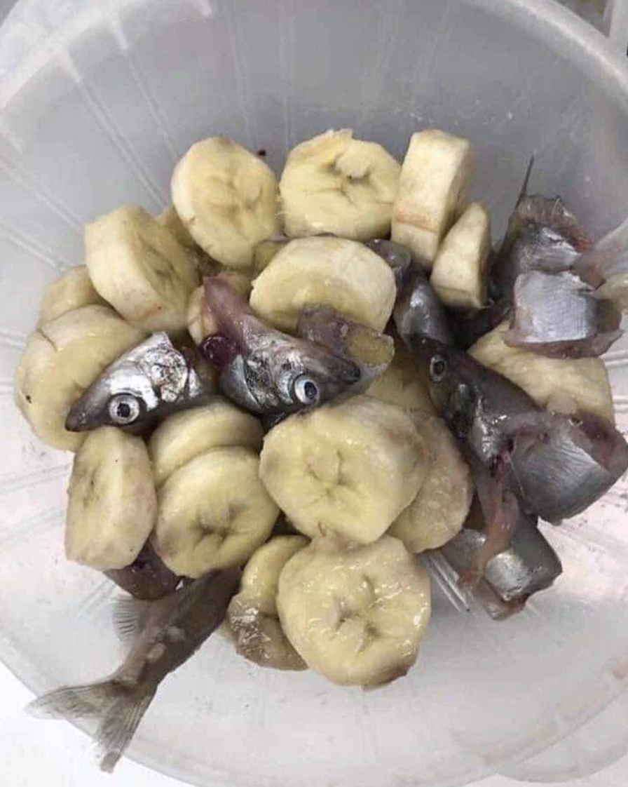 Bowl containing sliced bananas mixed with fish heads