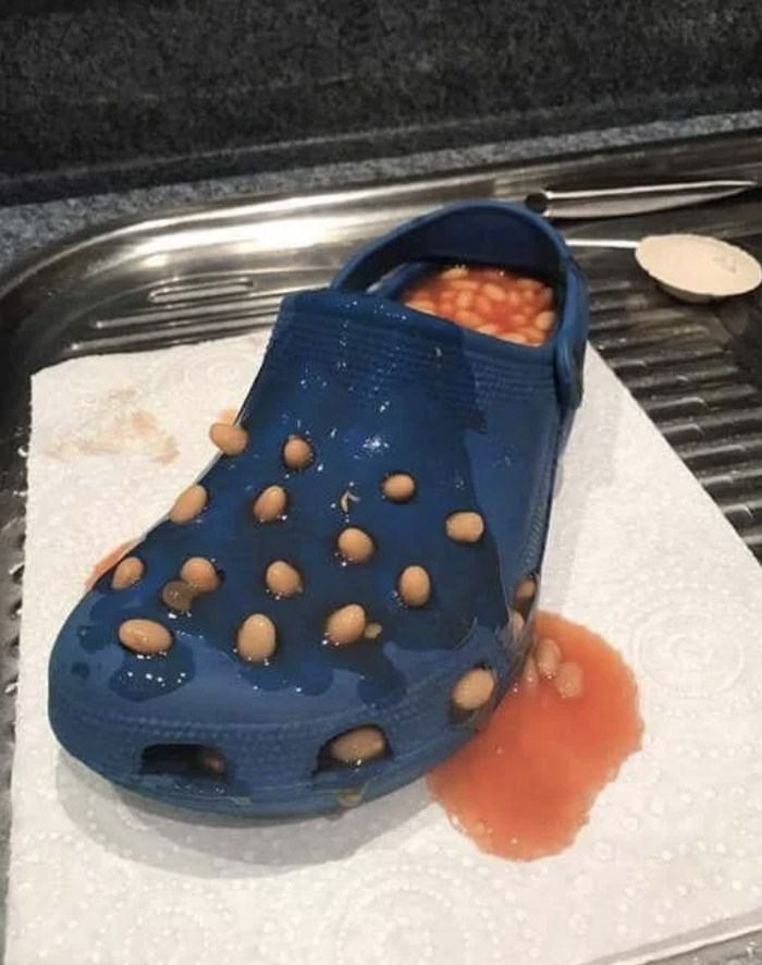 A porous shoe filled with beans coming through the holes and spilled sauce on a paper towel