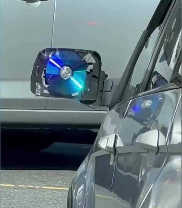 Reflective CD affixed to car side mirror, creating a makeshift blind spot mirror