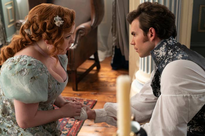 Two characters from Bridgerton in period costumes, a woman and a man, engaged in an intimate conversation