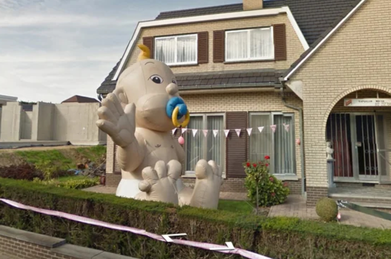 Inflatable baby figure in front of a house, likely celebrating a birth