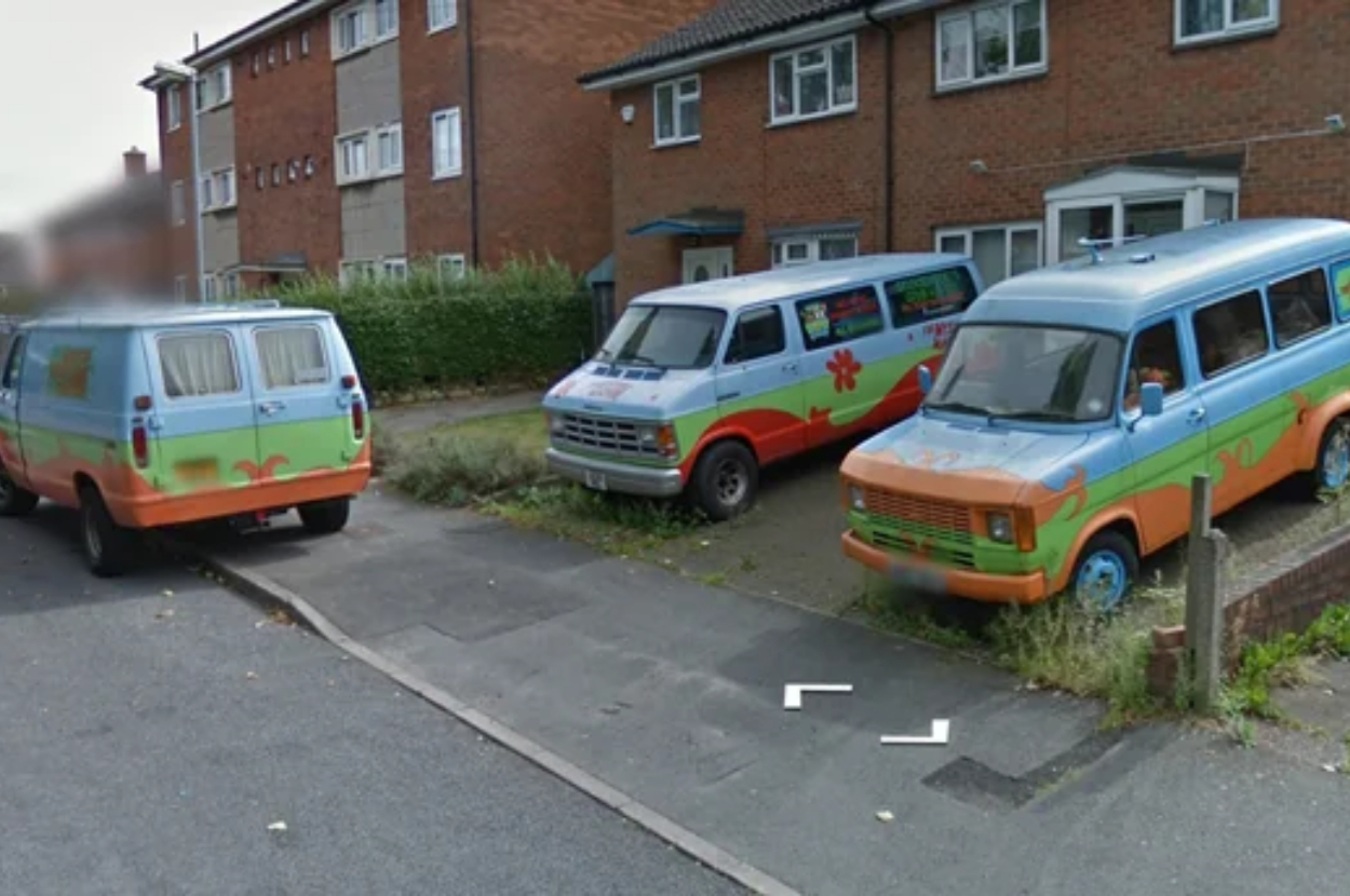 Two vans styled like the Mystery Machine from Scooby-Doo parked on a residential street