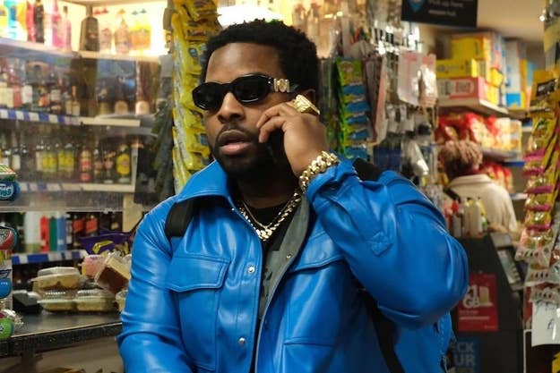 Man in a blue jacket and sunglasses talking on a phone, standing in a store