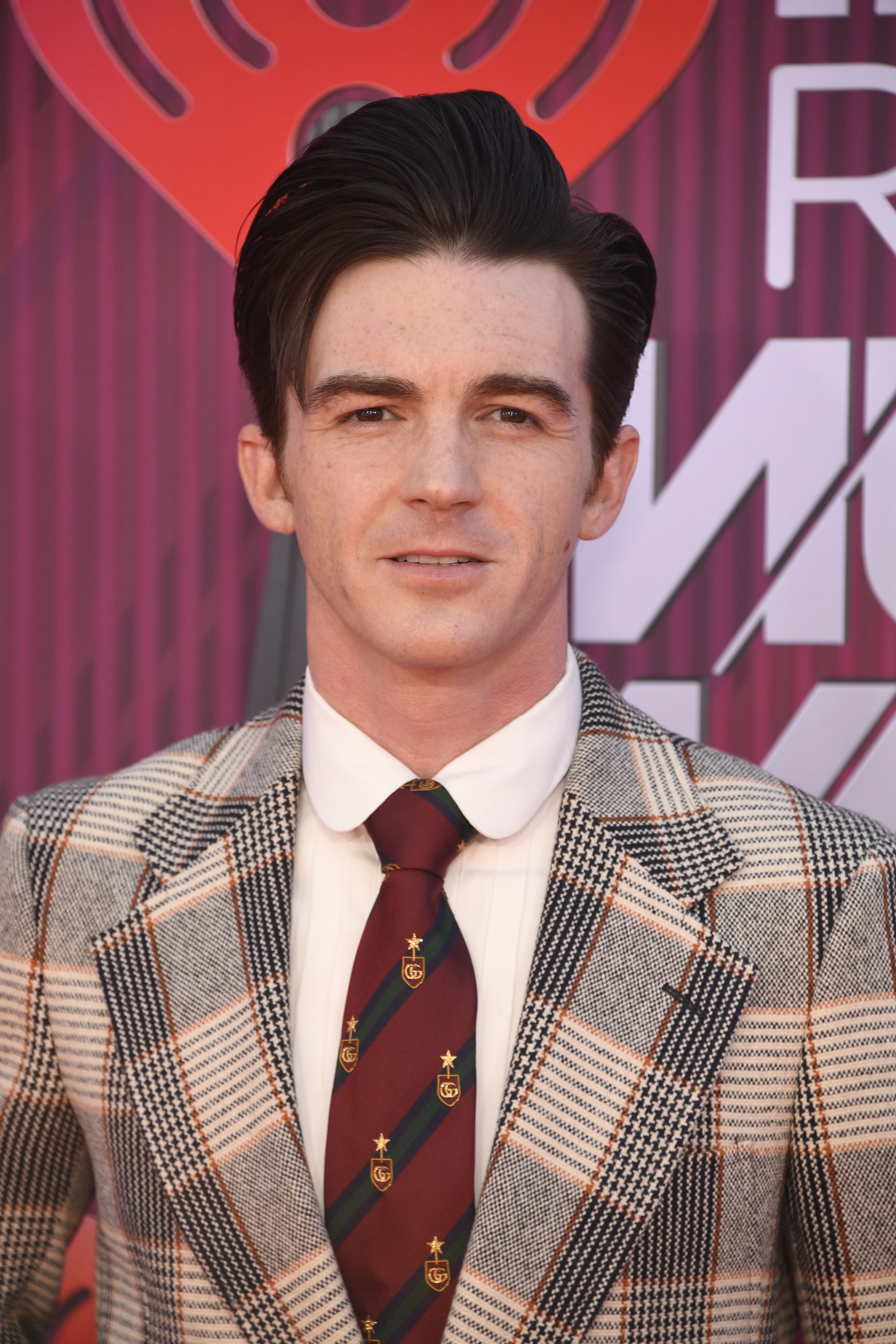 Drake in a plaid suit with a tie, posing at an event