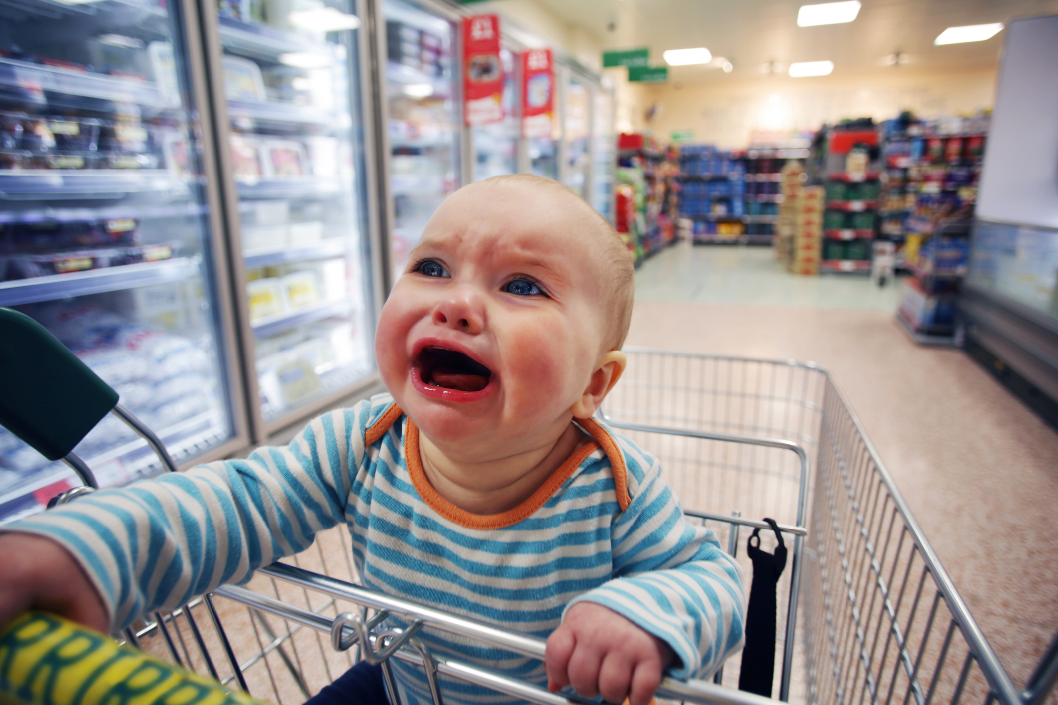 Baby crying in a shopping cart at a grocery store