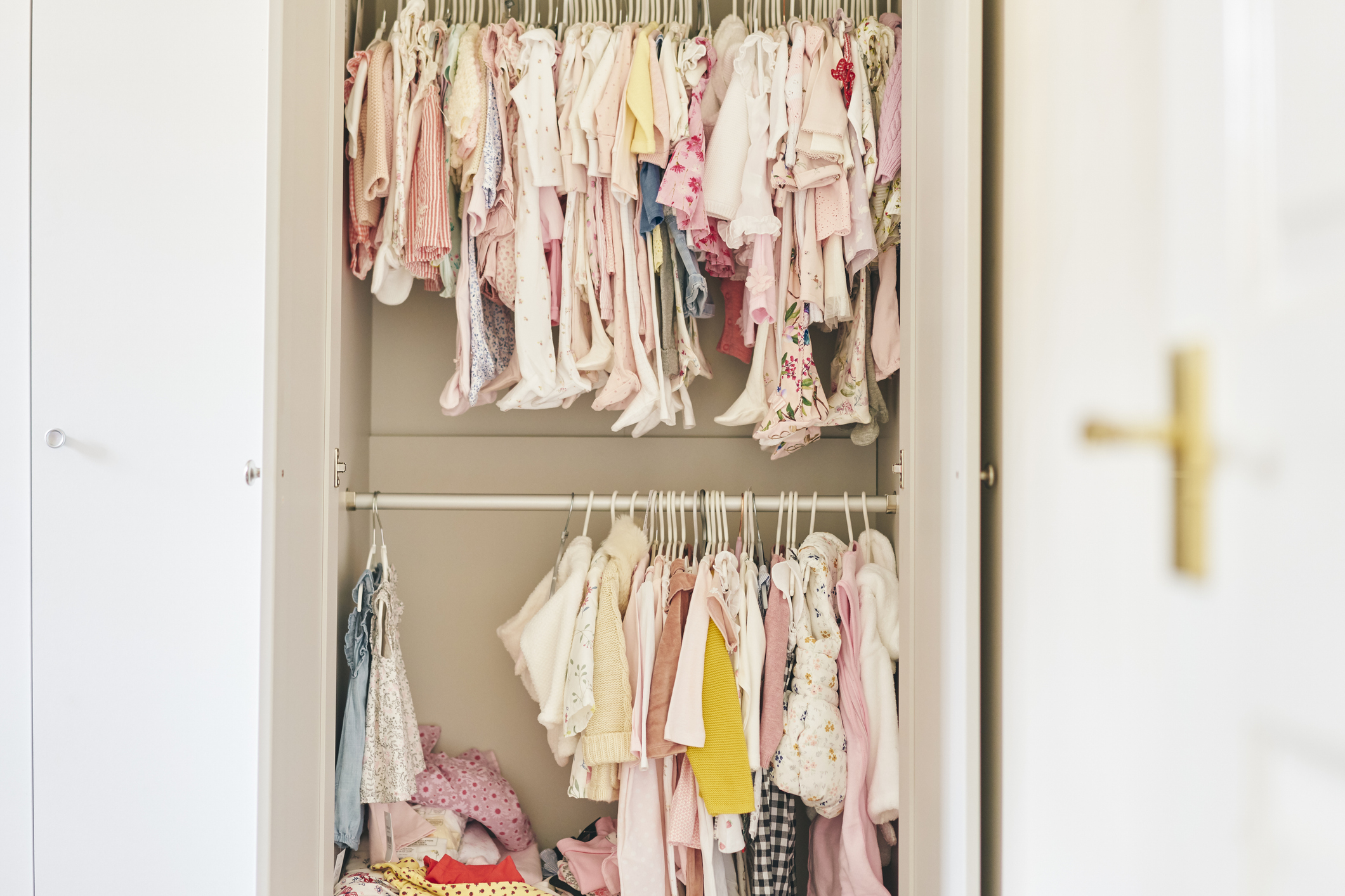 An open wardrobe filled with various children&#x27;s clothes neatly hanging