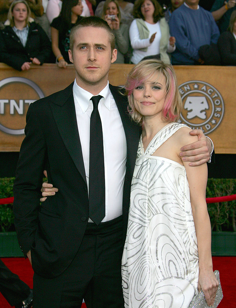 Ryan and Rachel standing together; him in a suit and shirt, her in a patterned dress