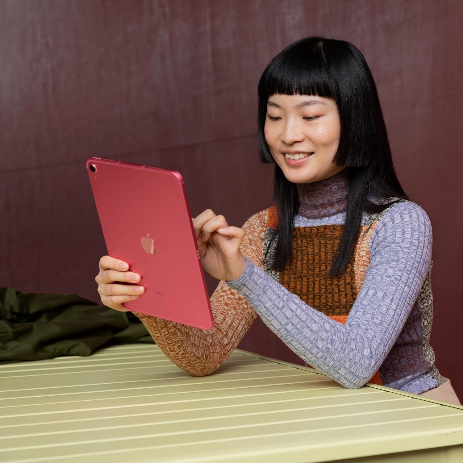 Model sitting, smiling at pink iPad